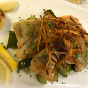 Teller mit Fischgericht und Gurkengemüse